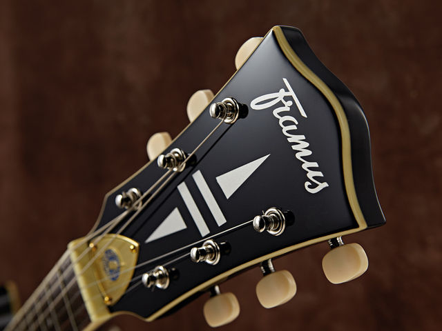 The split-diamond headstock motif is reminiscent of a Les Paul Custom. blank
