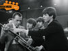 John Lennon and Ringo Starr look on as Paul McCartney shows Ed Sullivan the moves, 1964